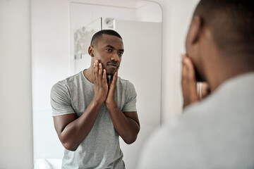 Young African American man touching his face in his bathroom - obrazy, fototapety, plakaty