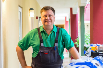 Clearing service in a hotel, male hotel worker in the corridor with a cart of things.