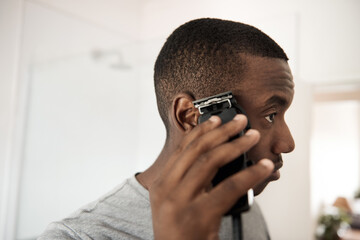 Young African man trimming his hair in his bathroom - obrazy, fototapety, plakaty