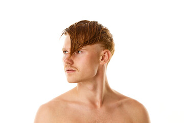 Portrait of naked man, young serious guy with red and wet hair looking away against white studio background.