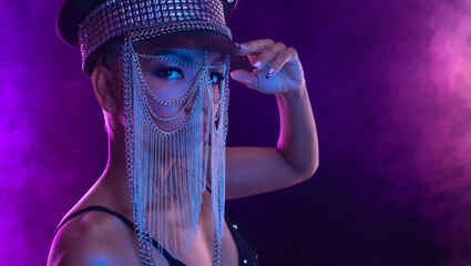 Hipster fashion girl, african american model wear headphones enjoy listen new cool music mix. Woman stand at purple studio background in trendy club purple party light with fog.