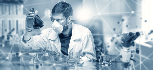 Man scientist. Virologist sits at table with test tubes and microscope. Guy scientist in white coat. Laboratory assistant does scientific research. Man scientist at work. Biologist in protective mask