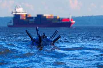 Anti-ship mine floats in water. Sea vessel approaches underwater bomb. Civilian cargo ship near wet...