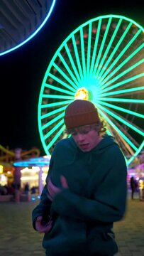 Vertical view of the joyful caucasian guy in hip hop outfit dancing into music under neon lights street