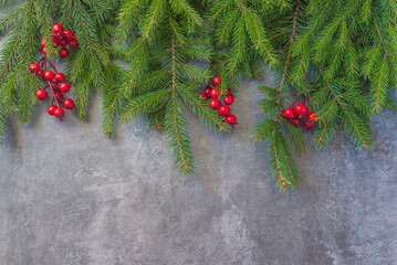 Fototapeta na wymiar Christmas holiday background; Frame of green fir twigs and red berries on the gray textured background; copy space