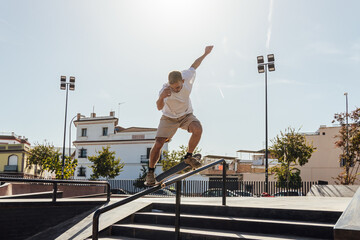Energetic man riding skateboard on rail in skate park