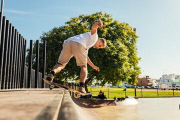 Energetic man riding skateboard on ramp in skate park