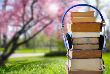 Relaxing with audiobooks during springtime season with heap of books and vintage headphones....