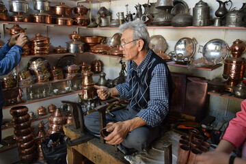 A tinsmith, in his, tinsmith's shop,The master, of working, with copper, in his shop