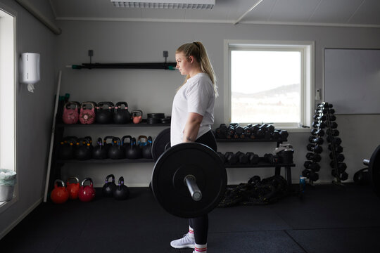 Mid adult woman lifting barbell in gym