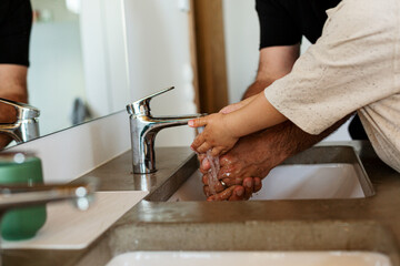 Mid section of father and child washing hands