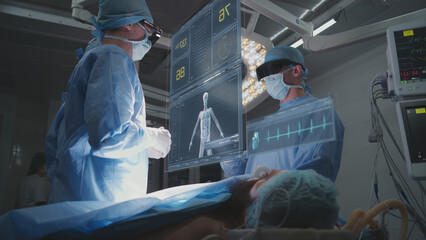 Doctors perform surgery in hospital operating room wearing AR headsets. 3D graphics of virtual AI holographic display showing vital signs and patient condition. VFX animation. Modern medicine concept.