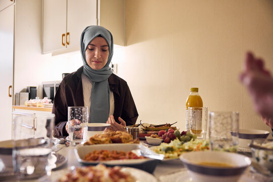 Woman in headscarf praying before meal