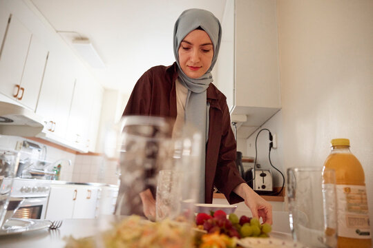 Woman in headscarf setting table for eid al-fitr at home
