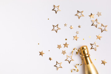 Champagne bottle with confetti stars and party streamers on white festive background. Christmas, birthday or wedding concept. Flat lay. - obrazy, fototapety, plakaty