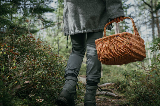 Low section of woman carrying wicker basket while walking by plant