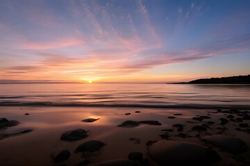 夕日が沈む夕焼けのビーチの岩場の美しい風景、水と砂に夕日が反射して輝いている