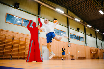 Female handball player jumping while throwing handball in sports court