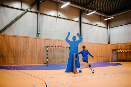 Female handball player running with ball in sports court