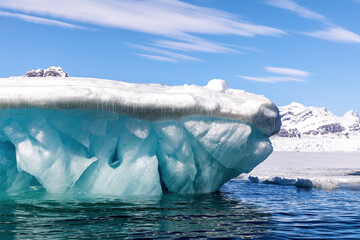 Glacial blue iceberg and sky background. Underside of a snow covered iceberg in Svalbard, a Norwegian archipelago between mainland Norway and the North Pole