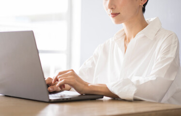 パソコン作業をしている日本人女性/白シャツを着ている