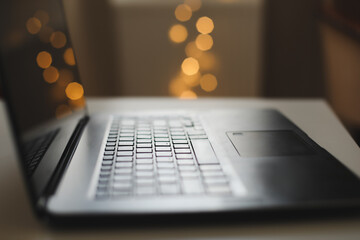 Close up of laptop keyboard with blank screen on a table by blurry bokeh lights background in the house or office modern, sunlight in morning