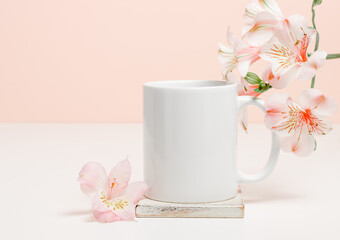 Mockup mug on wooden cup coaster with pink lily flowers, copy space. Mockup mug for logo, gift and design.