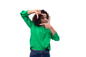 young positive caucasian lady with black curls is dressed in a green shirt in the studio