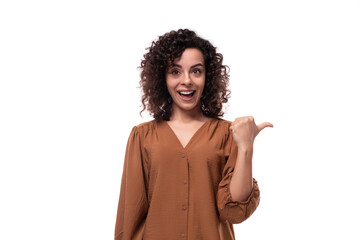 young surprised caucasian curly brunette woman dressed in a stylish brown blouse on a white background