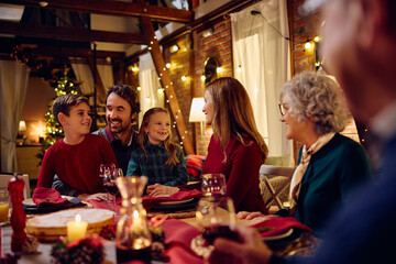 Happy multigeneration family enjoys while gathering at dining table for Christmas dinner.