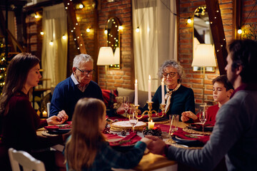 Multigeneration family saying grace before meal at dining table on Christmas. - obrazy, fototapety, plakaty