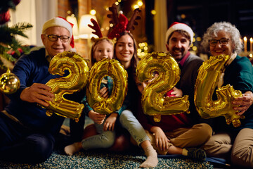 Close up of extended family holding 2024 balloons while celebrating New Year at home.