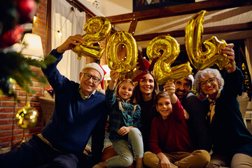 Happy multigeneration family celebrating 2024 New Year at home and looking at camera.