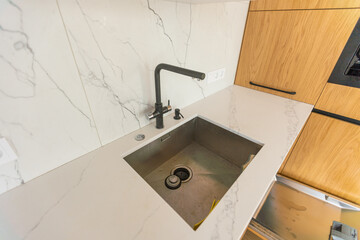Black kitchen sink and Tap water in the kitchen. The interior of the kitchen room of the apartment....