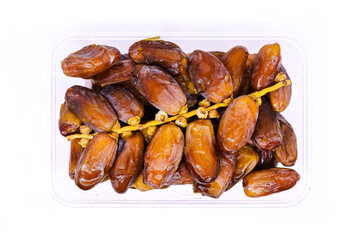 Close-up view of a Pile of large delicious Sukkari dates in a transparent food container to keep food hygienic isolated on white background. Arabic healthy food concept top view.