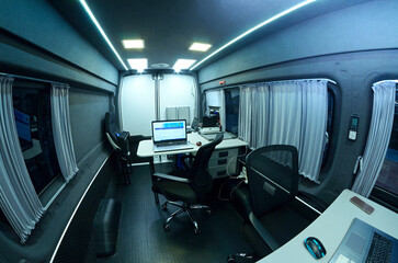 Obraz premium Mobile state administrative services office set in the interior of mini bus: laptops, monitors, phones, printer and other office devices