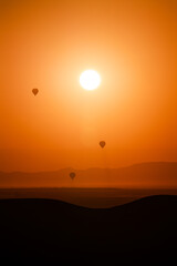 unset sunrise in the desert and air balloons in the sky flying to the sun