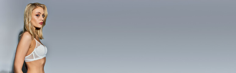 Obraz premium alluring young woman in sexy attire with blonde hair posing in profile and looking at camera, banner