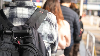 Close-up at back of a man with backpack bag during queue up and waiting to buy a attractive event...