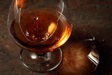 Brandy is in a broken glass on a rusty background.