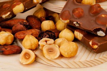 Primo piano di cioccolato al latte con fave di cacao nocciole su sfondo di legno