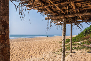 Fototapeta na wymiar coconut trees on ocean coast near tropical shack or open cafe on beach with sunbeds