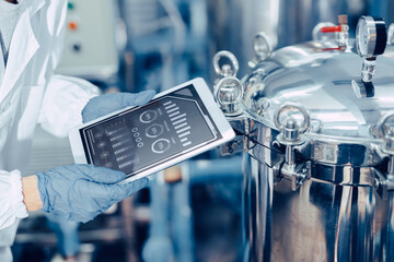 closeup engineer worker tablet in food and drinks factory industry monitor operate control inspecting production line high pressure tank production line. - Powered by Adobe