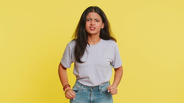 Irritated angry Indian woman screams from stress tension problems feels horror hopelessness fear surprise shock expresses rage nervous, quarrel. Arabian young girl isolated on yellow studio background