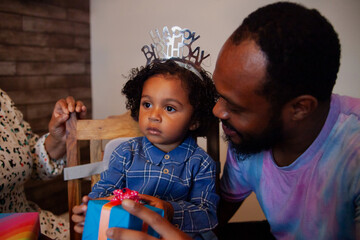 African father and biracial baby with birthday tiara holding present © Anna Neubauer