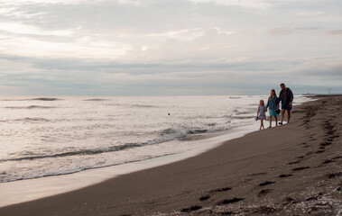 A family walks along the sandy beach. Sea coast.