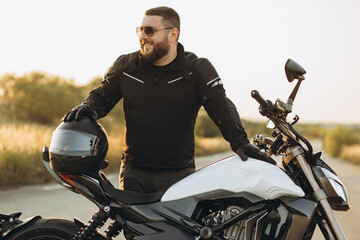 Man biker standing by his bike holding his helmet