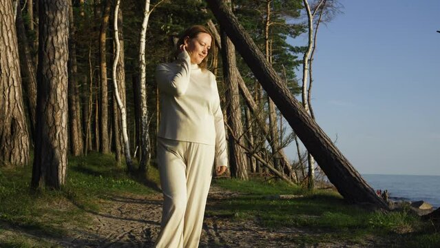 A woman walks in the evening at sunset along a forest path along the sea. Holidays at sea.