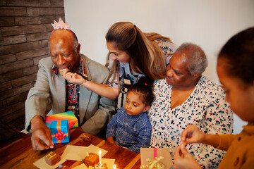 Black grandparents celebrating biracial grandson's birthday eating cake daughter in law