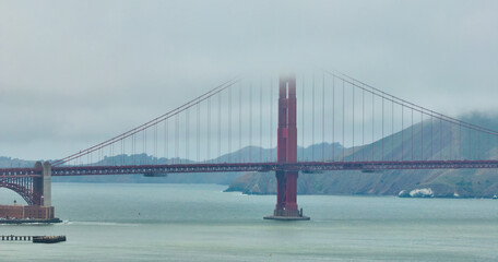 Golden Gate Bridge shrouded in cloudy mist on foggy day aerial over San Francisco Bay, CA